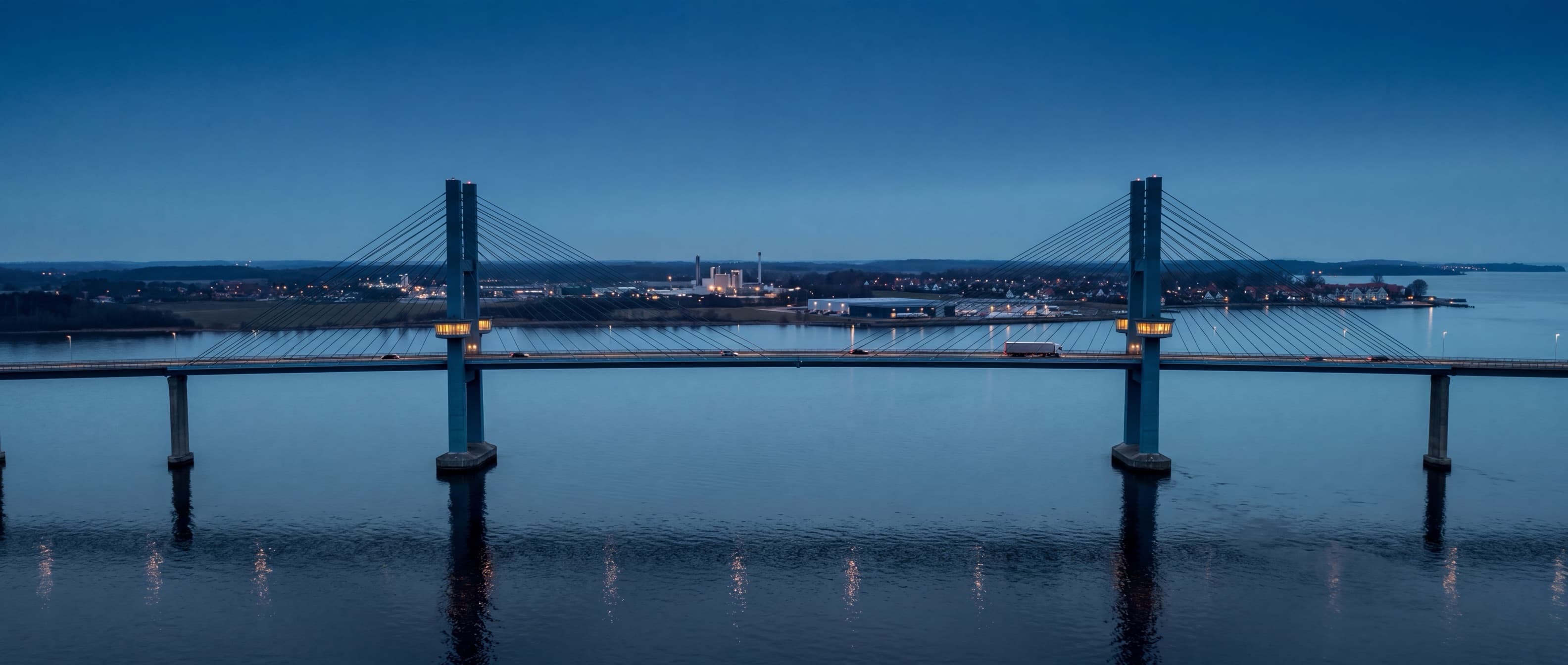 Schrägseilbrücke zur blauen Stunde, von der Seite gesehen, zwischen zwei Küsten